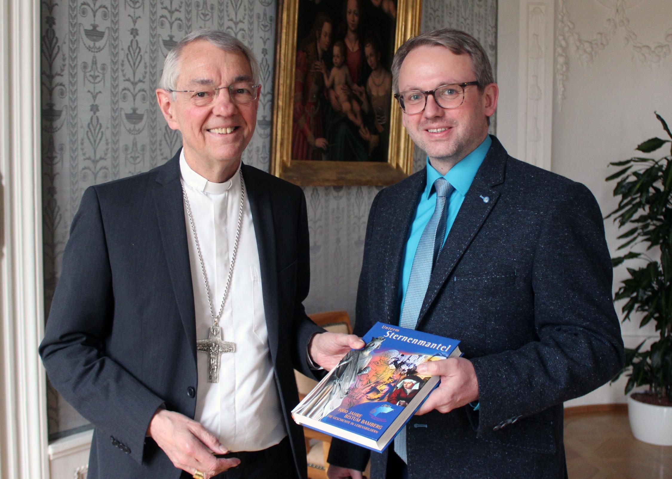Erzbischof Schick überreichte Marcus Pfalzer ein Buch über die Bistumsgeschichte. Marcus Pfalzer